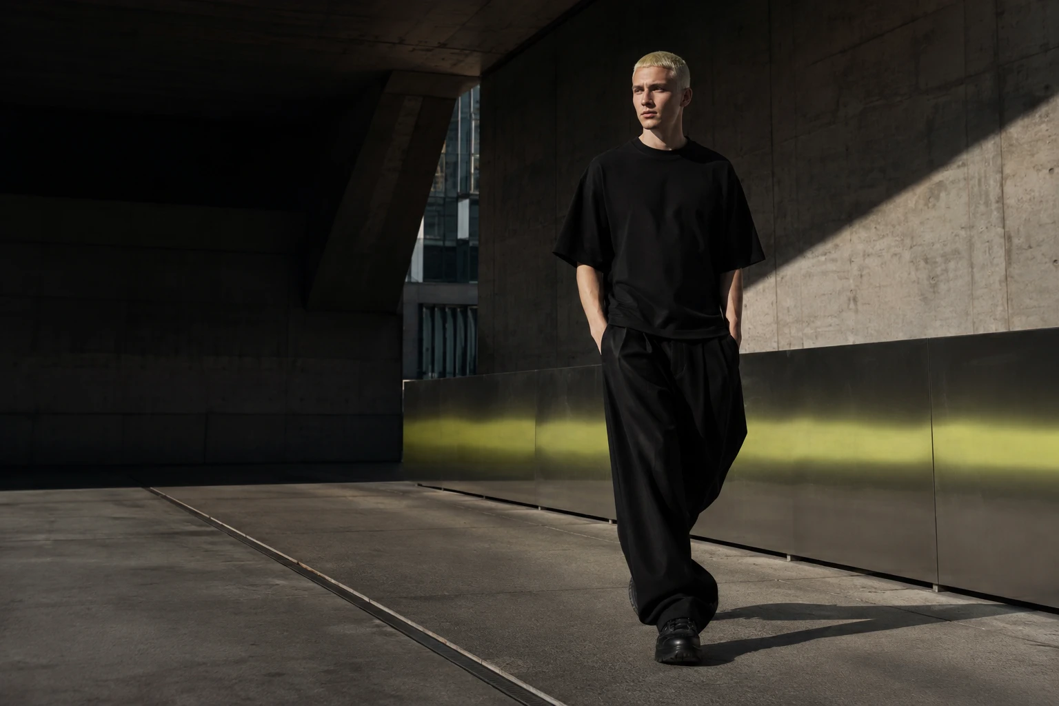 Modelo con silueta oversize negra para STRAKES en arquitectura brutalista